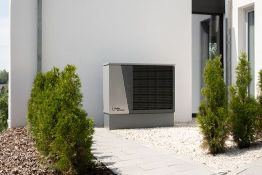 Installateur plaatst een hybride warmtepomp bij een woning in Rotterdam terwijl een huiseigenaar de subsidievoorwaarden bekijkt